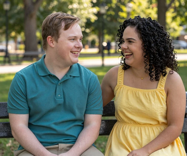 Daniel and Sophie, two adults with Down syndrome sharing a joyful moment on a park bench using BeyondLimits dating site