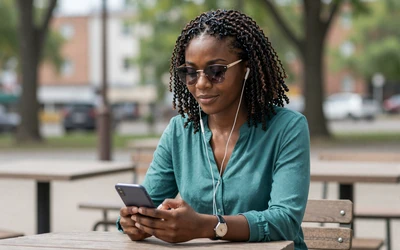 Blind woman using a smartphone with earbuds representing the blind people dating site